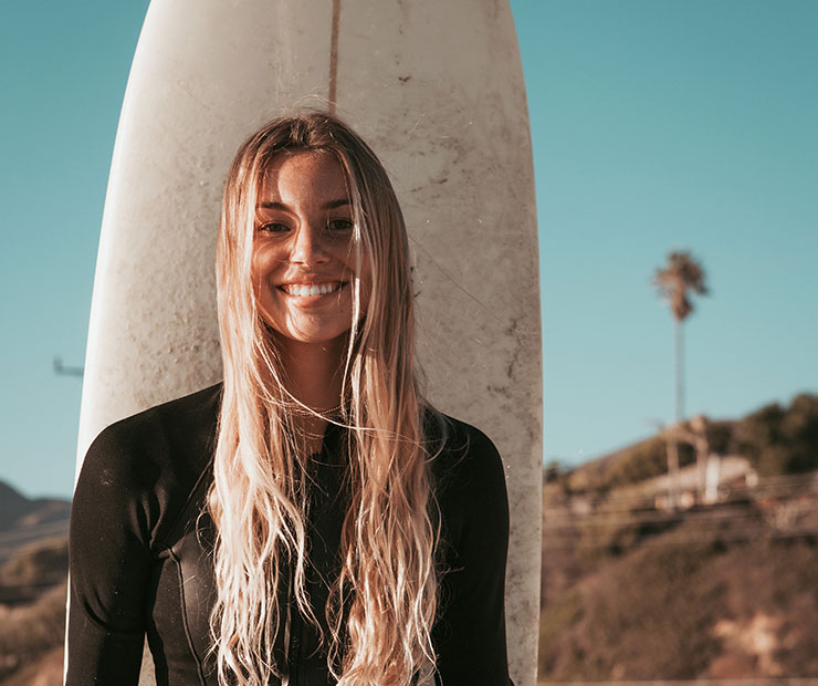 Surfer smiling with surfboard behind